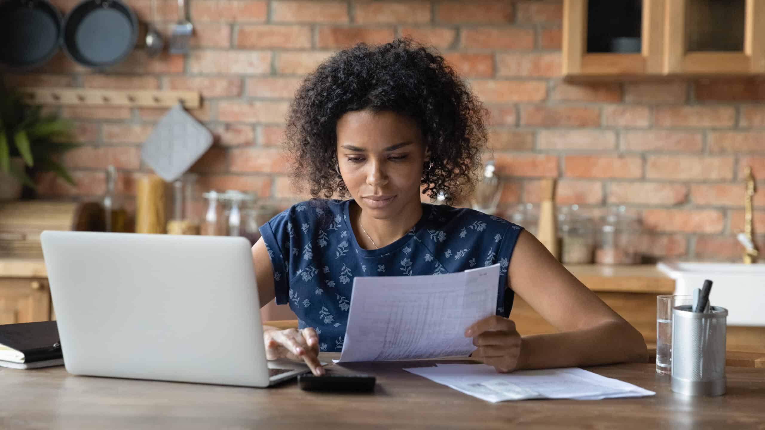 Vrouw zit thuis achter laptop belasting te berekeken